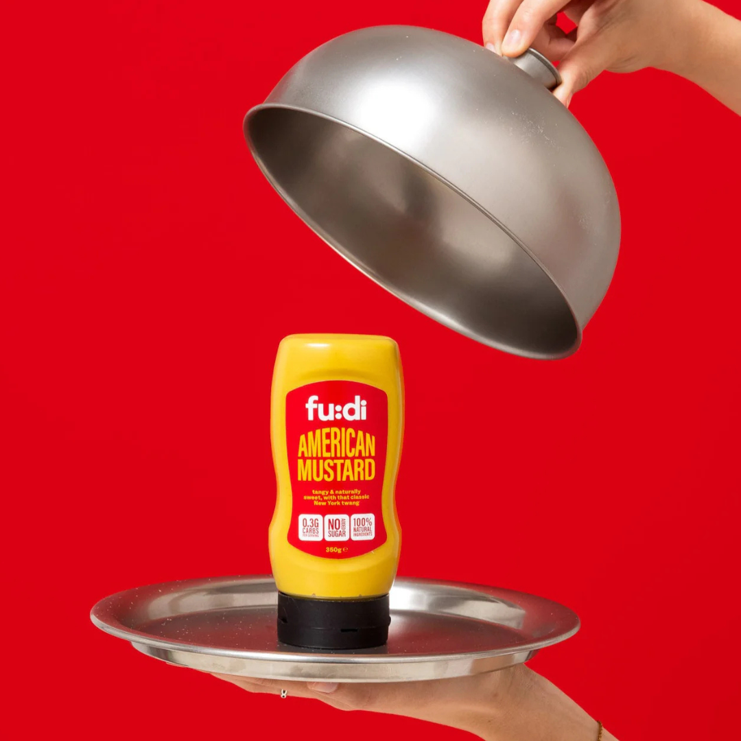 American mustard squeeze bottle on a silver serving tray with dome lid against a bright red background